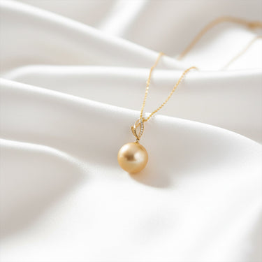 Gold necklace with a pearl pendant on a white fabric background